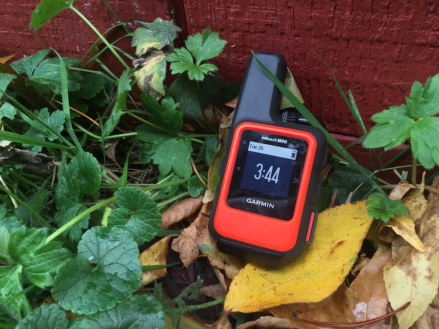 The Garmin inReach Mini outside in the grass with the home screen powered on.