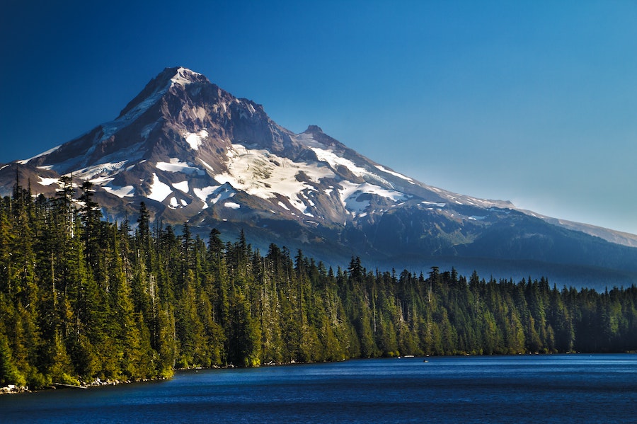 A view of Mount Hood in Oregon with a lake and forest in the foreground.