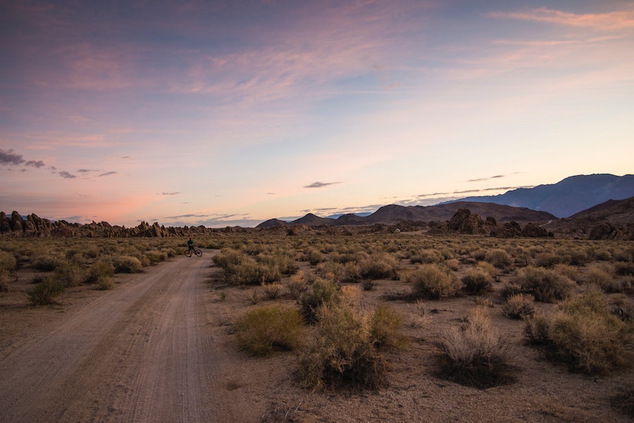 Person bicycling down dirt road on BLM land near Alabama Hills in California.
