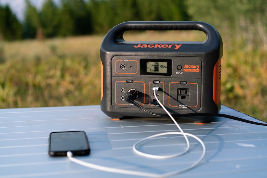 Jackery Explorer 500 portable power station charging an iPhone on a portable camping table.
